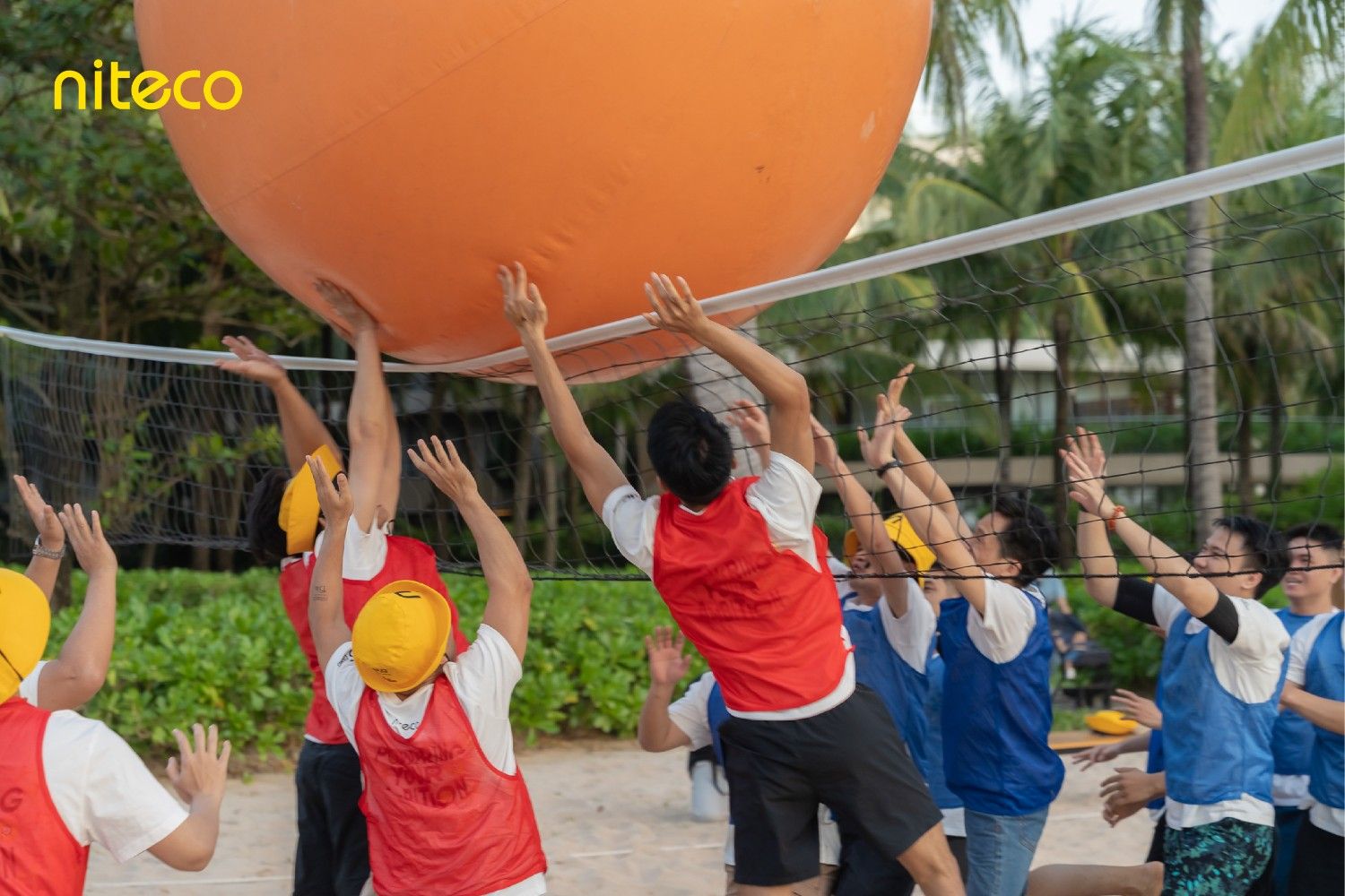 Team lifting a giant inflatable ball during a beach team-building game