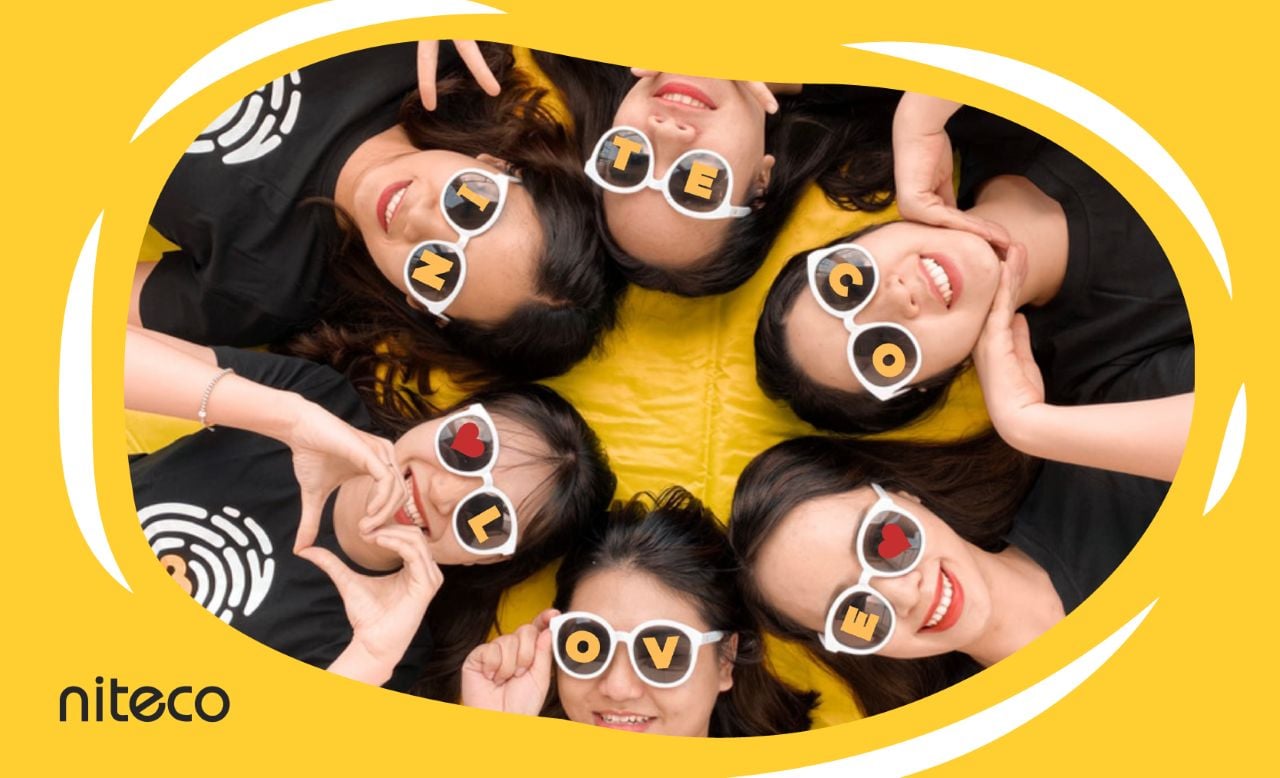 Niteco team wearing sunglasses spelling "NITECO LOVE" smiling on yellow background