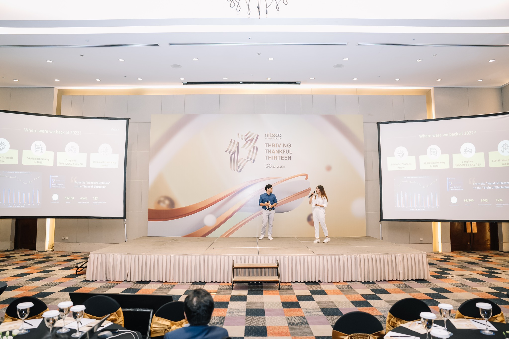 Niteco 13th anniversary event with speakers on stage and presentation screens