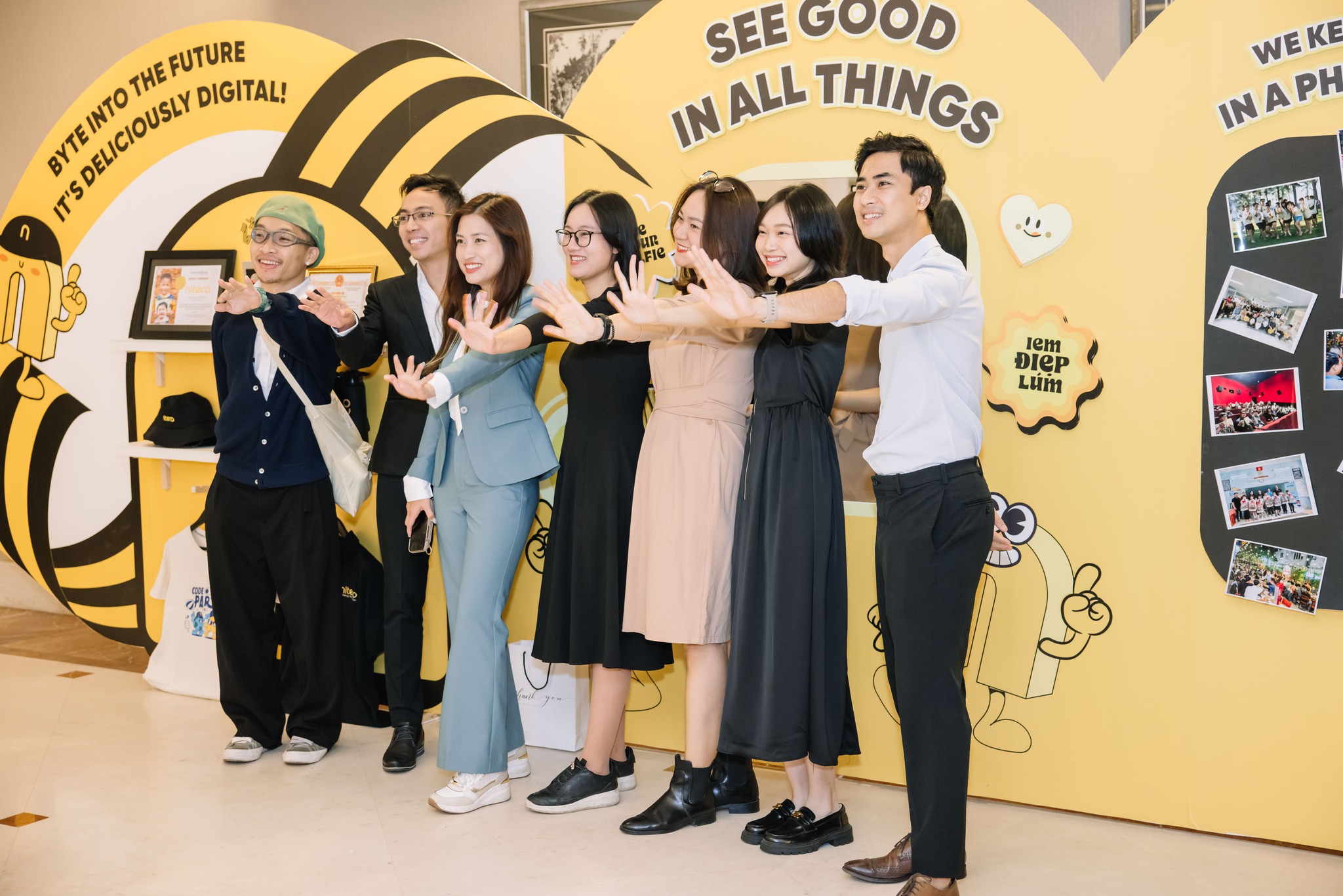 Group of young professionals posing smiling in front of yellow digital innovation backdrop