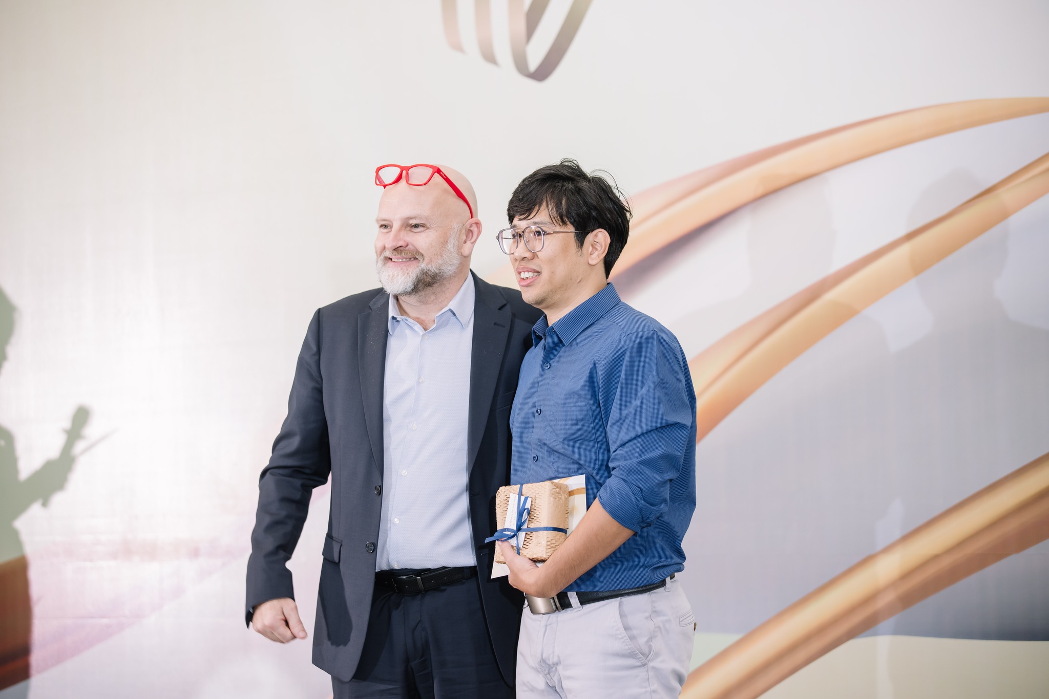 Two men smiling during award ceremony holding gift and certificate
