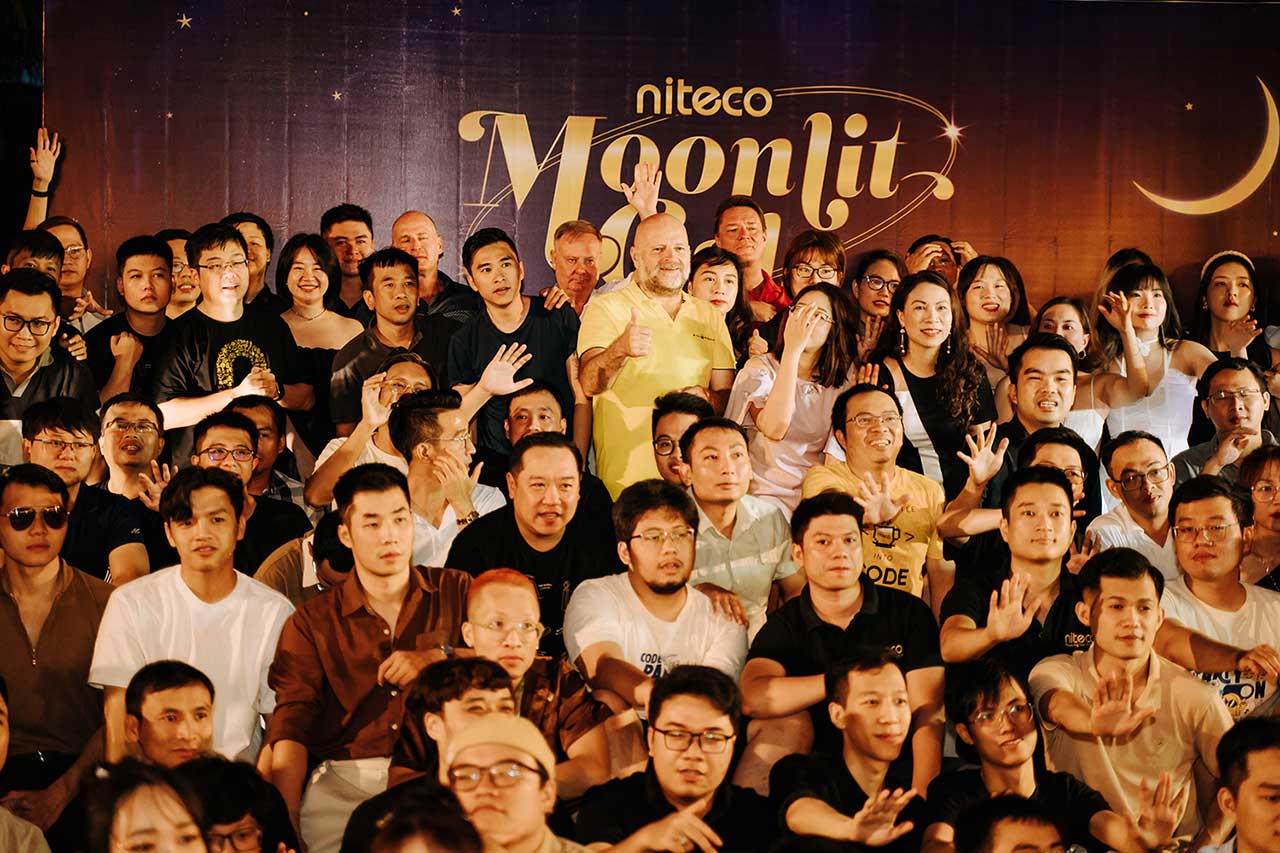 Niteco Moonlit event group photo with diverse participants and crescent moon backdrop