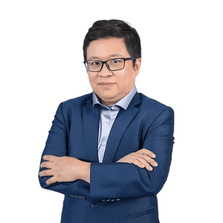 Confident professional man in blue suit with glasses, posing with arms crossed