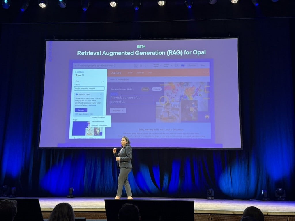 A person on stage with a large screen

Description automatically generated