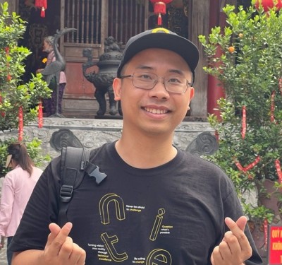 Young man smiling and making heart signs in front of a traditional temple entrance
