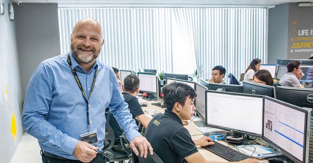 Man in blue shirt leading software development team in modern office setting