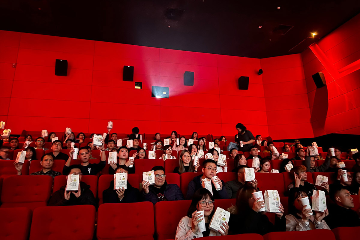 Movie theater audience holding popcorn and drinks inside a red cinema hall